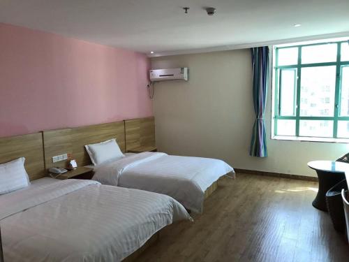 a hotel room with two beds and a window at 7Days Inn Shenzhen Sha Mei Metro Station in Shenzhen