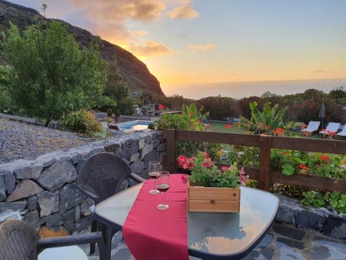 a table with a red table cloth on a stone wall at Viña Camello in Buenavista del Norte
