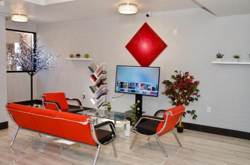 a room with red chairs and a glass table and a tv at Ramada by Wyndham Yuma in Yuma