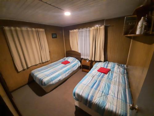 Habitación pequeña con 2 camas y almohadas rojas. en casa completa Balmaceda 77, en Concepción