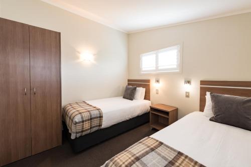 a small bedroom with two beds and a window at Suncourt Hotel & Conference Centre in Taupo