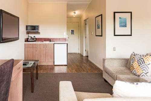 a living room with a couch and a kitchen at Suncourt Hotel & Conference Centre in Taupo