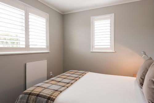 a bedroom with two windows and a bed at Suncourt Hotel & Conference Centre in Taupo