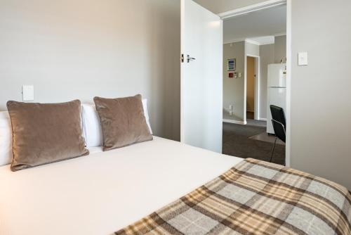 a bedroom with a large white bed with two pillows at Suncourt Hotel & Conference Centre in Taupo