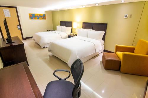 a hotel room with two beds and a couch at Sonesta Hotel Cali in Cali