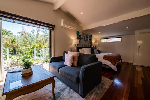 a bedroom with a bed and a couch and a table at Araluen Boutique Accommodation in Yarra Glen