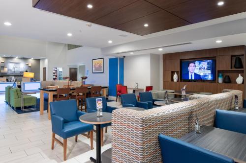 a restaurant with blue chairs and tables and a flat screen tv at Holiday Inn Express Hotel & Suites Dallas South - DeSoto by IHG in DeSoto
