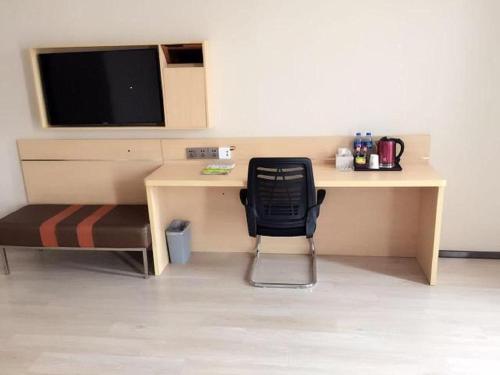 a desk with a chair and a television on a wall at 7Days Premium Tangshan Fengnan Shuang Lake Jinyuan in Tangshan