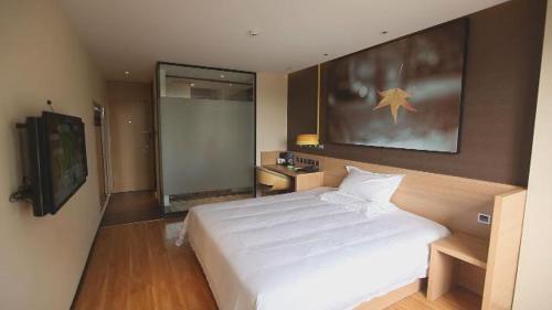 a bedroom with a large white bed and a television at 7Days Inn Zhangjiakou Chongli Yuxing Road in Zhangjiakou