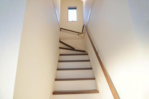 a staircase in a white building with a window at Muji House Osaka Sannan Hotel 大阪泉南酒店良築 in Tannowa