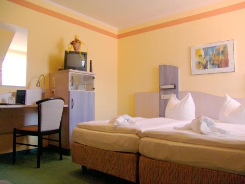 a hotel room with two beds and a chair at Oder-Hotel in Schwedt