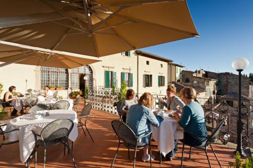 a group of people sitting at tables on a patio at Palazzo Leopoldo Dimora Storica & Spa in Radda in Chianti
