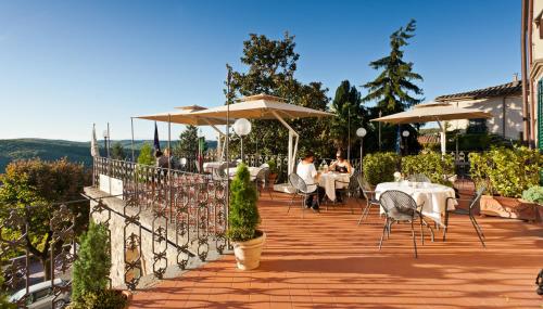 a patio with tables and chairs and umbrellas at Palazzo Leopoldo Dimora Storica & Spa in Radda in Chianti
