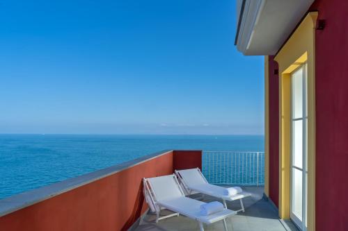 two white chairs on a balcony overlooking the ocean at Hotel Lorelei Londres in Sorrento