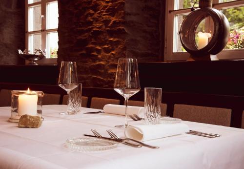 a table with two wine glasses and a candle on it at Landhaus Halferschenke in Dieblich