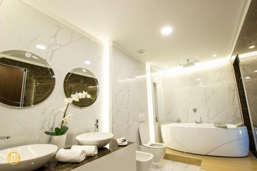 a white bathroom with two sinks and a tub at Hotel Fantasy in Gjirokastër