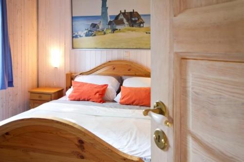 a bedroom with a wooden bed with two orange pillows at Ferienhaus 67 am Granzower See in Mirow