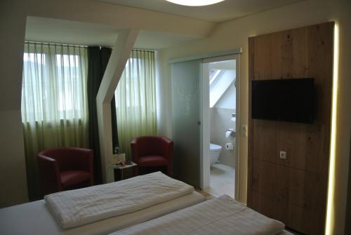 a bedroom with a bed and a television and a bathroom at Hotel Jägerhof in Weibersbrunn