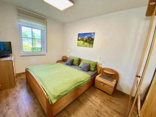 Schlafzimmer mit einem Bett mit grüner Bettwäsche und einem Fenster in der Unterkunft Ferienwohnung Winklmoos in Schönau am Königssee