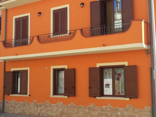 an orange building with brown shutters on it at Capo d'Orlando Apartments in Capo dʼOrlando