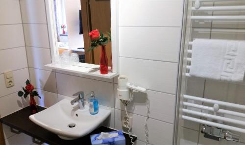 a white bathroom with a sink and a mirror at Hotel-Pension Grüne Linde in Delitzsch