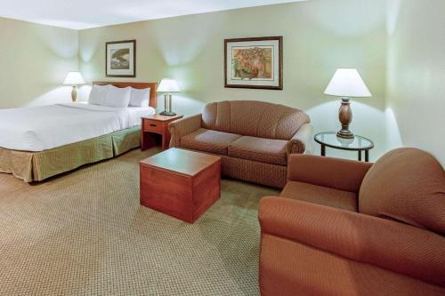 a hotel room with a bed and a couch and chair at La Quinta by Wyndham Appleton College Avenue in Appleton