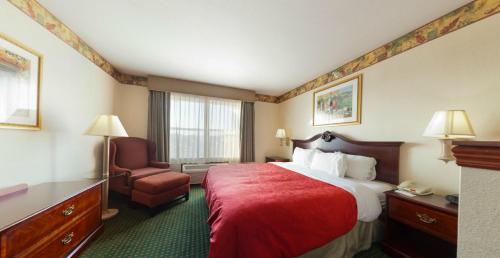a hotel room with a red bed and a chair at Country Inn & Suites by Radisson, Elkhart North, IN in Elkhart