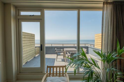 a room with a balcony with a view of the ocean at Poort Beach Boutique Apartments in Bloemendaal Aan Zee