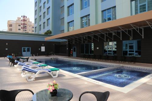 una piscina con tumbonas y un edificio en The Olive Hotel, Juffair, en Manama