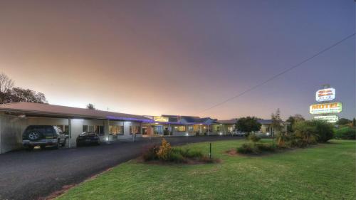a motel with a parking lot and a sign at Glen Innes Motel in Glen Innes