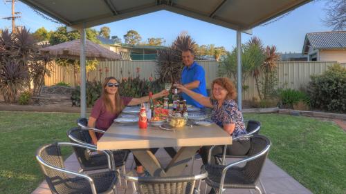 three people sitting at a table under an umbrella at Glen Innes Motel in Glen Innes