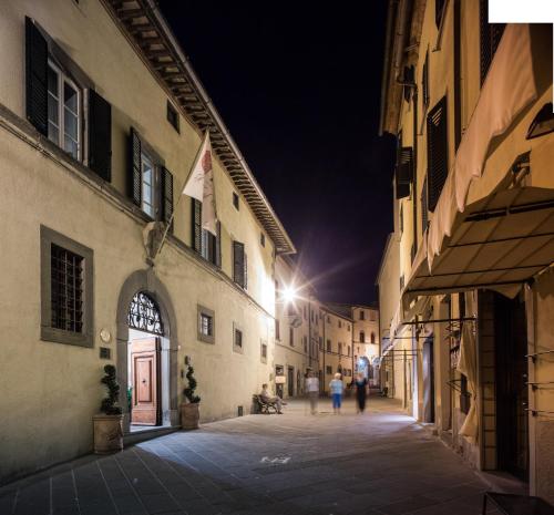 a street at night with people walking down the street at Palazzo Leopoldo Dimora Storica & Spa in Radda in Chianti