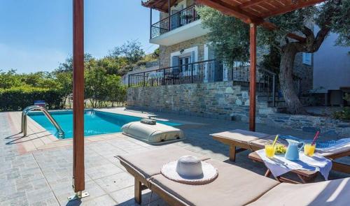 un patio trasero con piscina y una casa en Villa alegria, en Skopelos Town