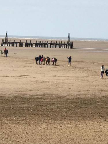 a group of people walking on a beach with a pier at Beach Lookout - SEA VIEWS in Lytham St Annes