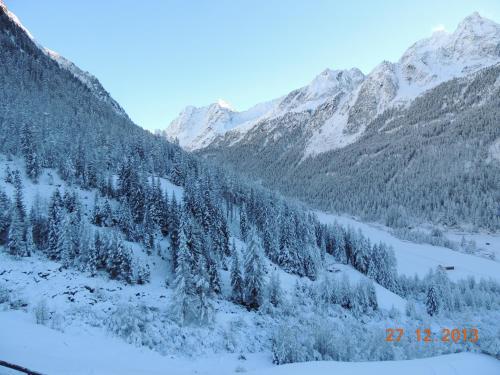 a snowy mountain range with trees and snow covered mountains at Pension Winnebach in Längenfeld