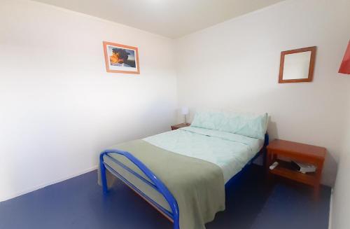 a small bedroom with a bed and a table at Tongariro River Retreat in Turangi