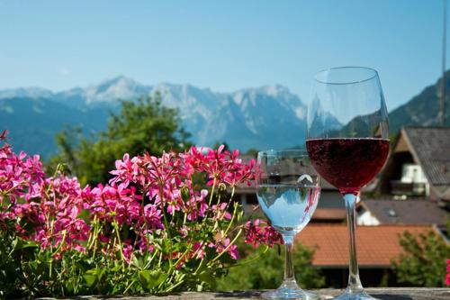 two glasses of wine sitting on a table with flowers at Hotel Gasthof Alter Wirt in Farchant