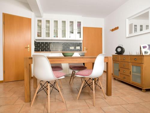 a kitchen with a wooden table and white chairs at FIP Park Achtern Diek in Insel Poel