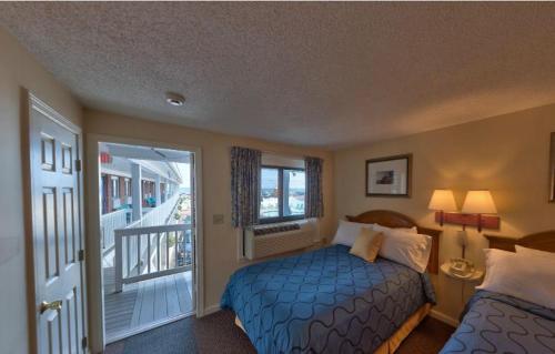 1 dormitorio con cama azul y balcón en Sands By The Sea Motel en York Beach