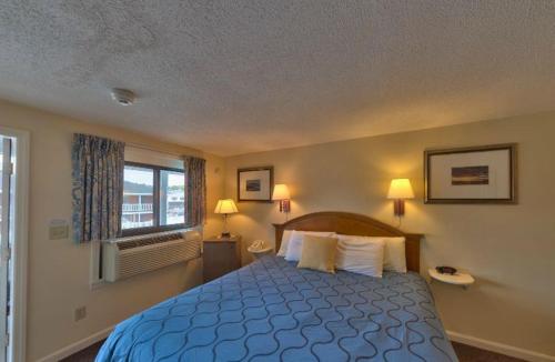 a bedroom with a blue bed and a window at Sands By The Sea Motel in York Beach