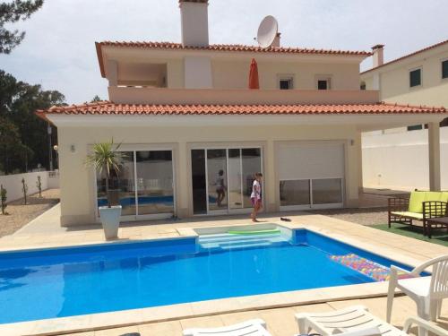 una persona parada frente a una casa con piscina en Villa dos Eucaliptos - Sao Martinho do Porto, en São Martinho do Porto