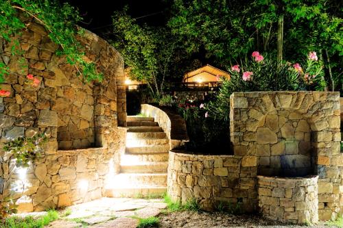 a stone wall with stairs and flowers on it at Delle Rose Camping & Glamping Village in Isolabona