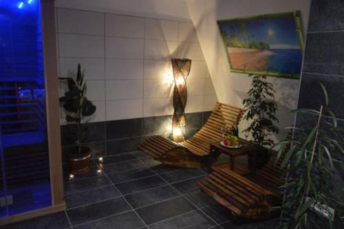 ein Zimmer mit zwei Bänken, einer Lampe und Pflanzen in der Unterkunft Hotel Kolonie in Frýdlant nad Ostravicí