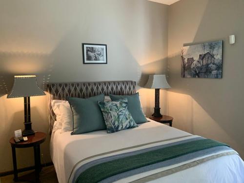 a bedroom with a bed with two lamps on tables at La Gratitude Self catering cottage in Franschhoek