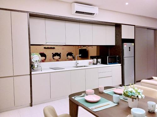 a kitchen with white cabinets and a table at Dorsett Residences Kuala Lumpur in Kuala Lumpur