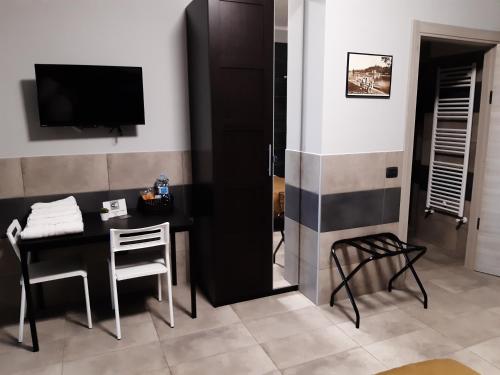 Habitación con mesa, TV, mesa y sillas. en La Montrucca Camere, en Caselle Torinese