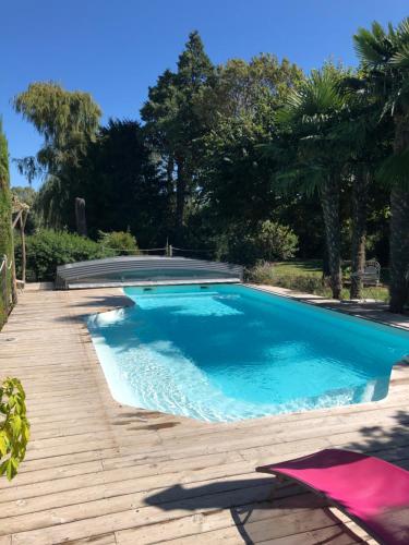 a large swimming pool with a wooden walkway and trees at Gite STANDING climatisé avec piscine chauffée et SPA PRIVATIF in Alzonne