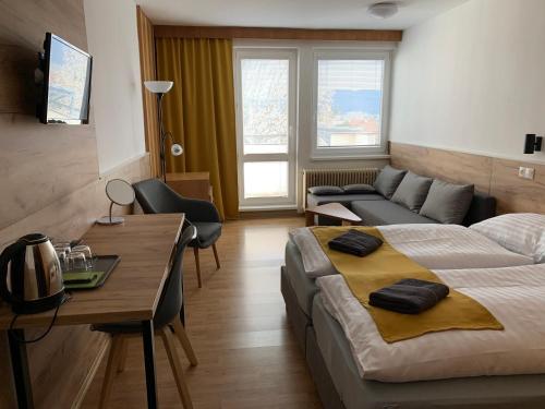 ein Schlafzimmer mit einem Bett, einem Schreibtisch und einem Sofa in der Unterkunft Penzión MADO I in Bojnice