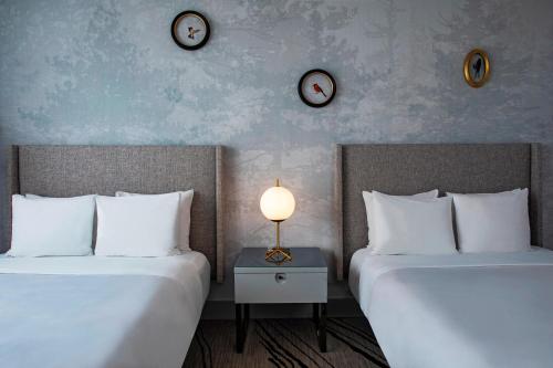 two beds in a room with clocks on the wall at The Starling Atlanta Midtown, Curio Collection by Hilton in Atlanta