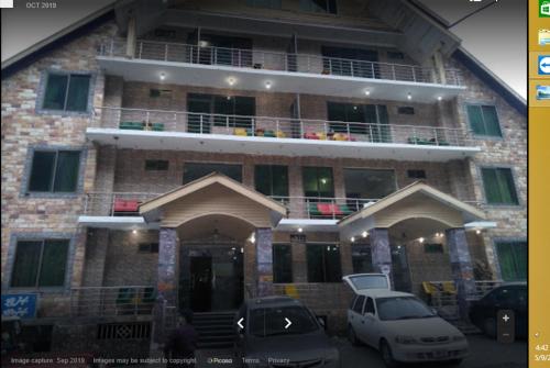 a building with two cars parked in front of it at Centurion Hotel in Nārān